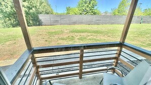 A covered patio with a concrete floor, metal railings, and two metal chairs. - Mid city huntsvegas studio #2 (Huntsville)
