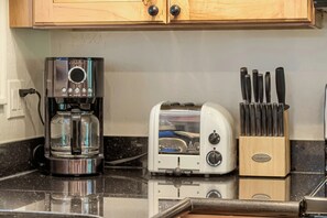 Una cocina con cafetera, tostadora y bloque de cuchillos.
