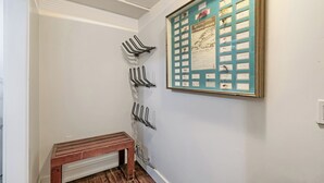 Un couloir avec un porte-manteau fixé au mur, muni de plusieurs crochets, un banc en bois et un présentoir encadré contenant des objets de collection sur la pêche à la mouche.
