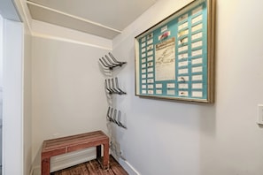 Ein Flur mit einem an der Wand befestigten Hakenständer, einer Holzbank und einer gerahmten Sammlung von Ausstellungsstücken zum Thema Fliegenfischen.