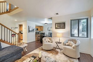 A spacious living room with a staircase, a dining area, and a kitchen.