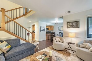 A spacious living area with a wooden staircase, a dining area, and a kitchen.
