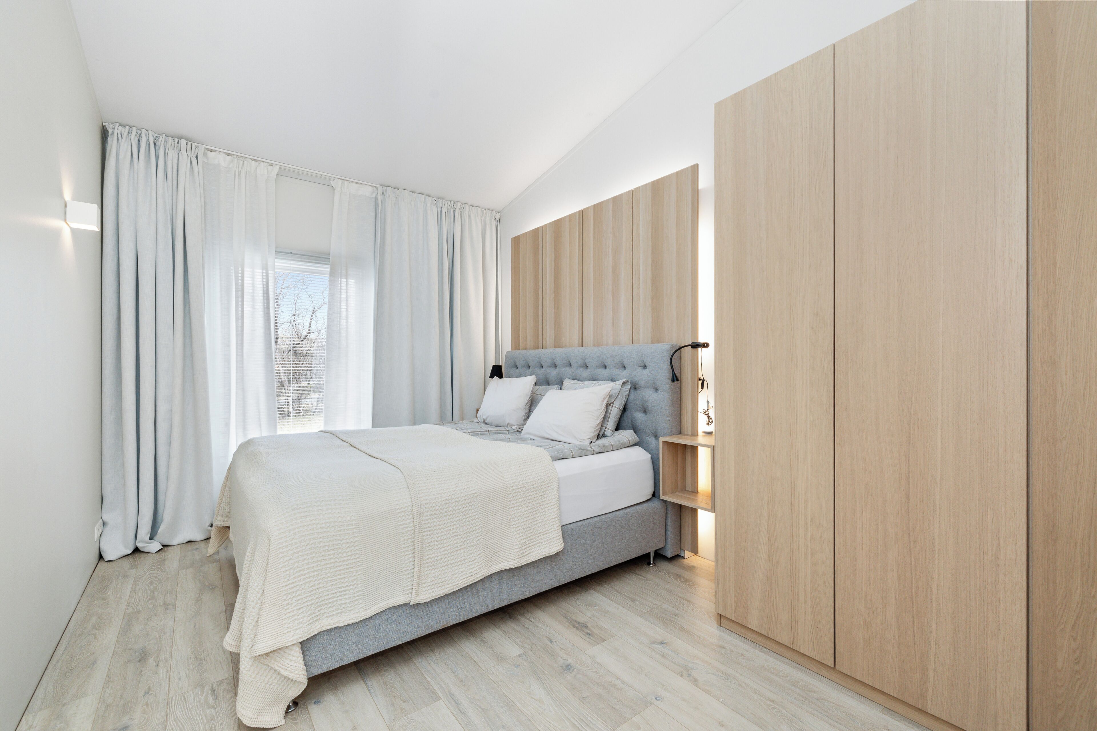 Quarto moderno com uma cama, mesa de cabeceira e guarda-roupa.