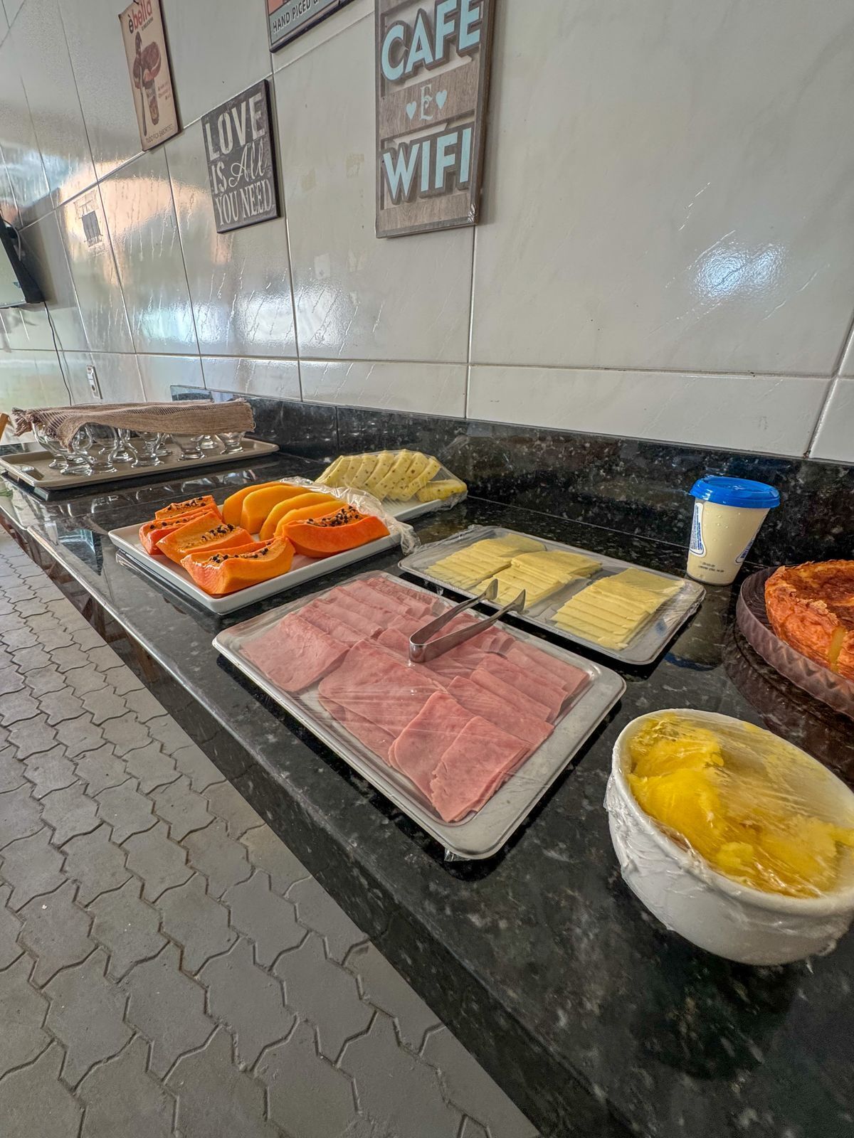 A buffet with various food items including sliced fruits, meats, and a bowl of yellow food.