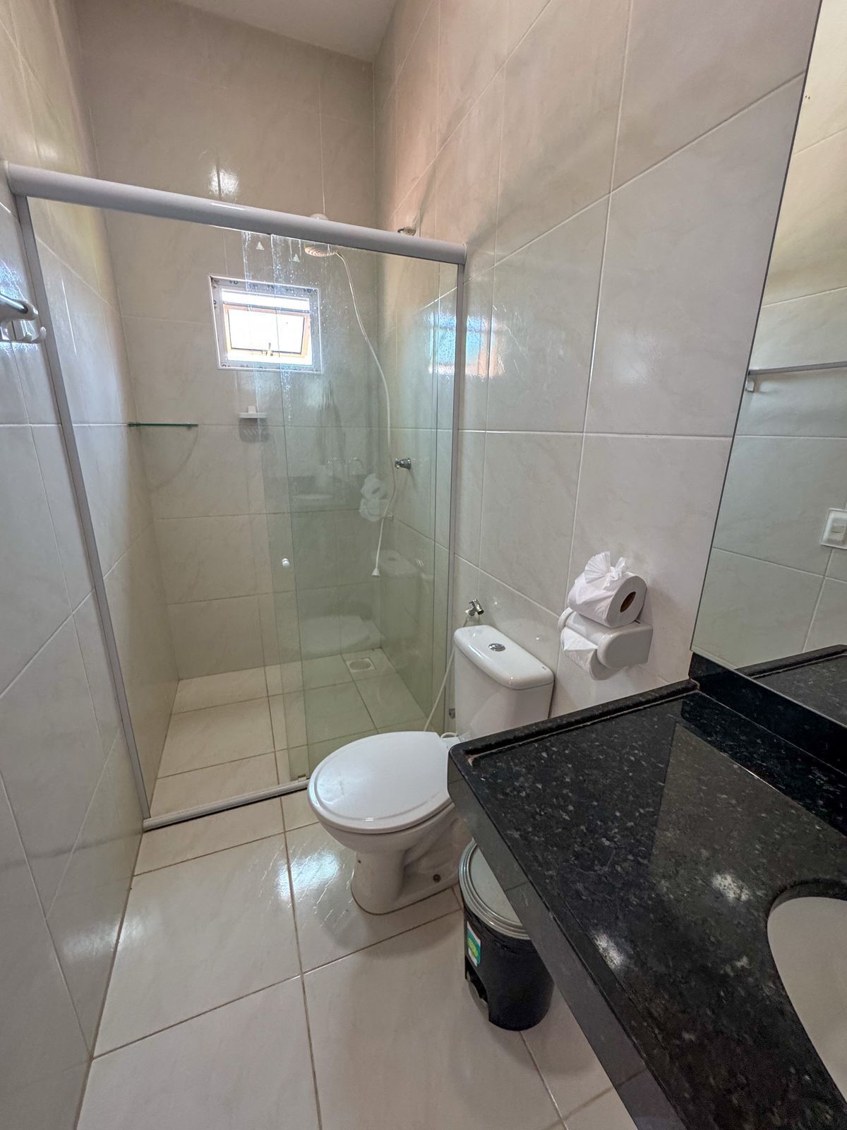 A bathroom with a glass-enclosed shower, a toilet, and a sink with a black countertop.