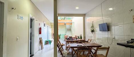 A hallway with a dining area featuring wooden tables and benches, a staircase leading to an upper level, and a fire extinguisher on the wall.