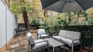 Un patio al aire libre con un sofá gris, dos sillones y una mesita.