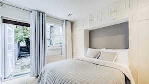 Un dormitorio con una cama grande, una ventana con cortinas y vistas al exterior.