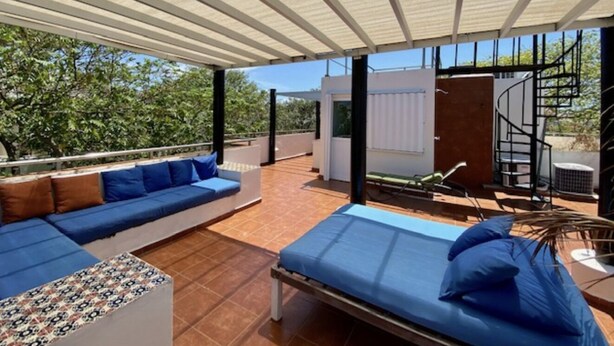 A modern outdoor living area with a sofa and a bed, a staircase, and a view of the surrounding trees. - Bosque de los Aluxes by BVR (Playa del Carmen)