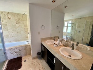 A modern bathroom with two sinks, a large mirror, and a shower area.