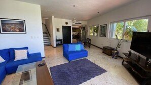 A spacious living room with a large TV, two blue sofas, a coffee table, and a staircase leading to another level. - Bosque de los Aluxes by BVR (Playa del Carmen)