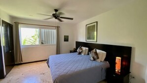 A bedroom with a bed, a ceiling fan, a nightstand, and a window with curtains. - Bosque de los Aluxes by BVR (Playa del Carmen)