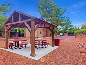 A covered picnic area with benches and a basketball court.