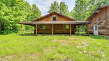 A rustic log cabin with a covered porch and a small attached shed.