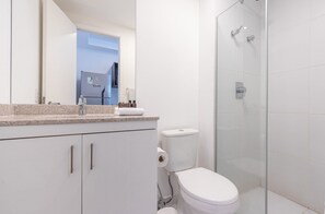 Een moderne badkamer met toilet, douche en wastafel.