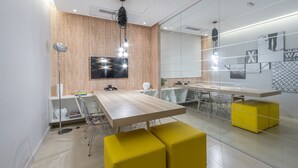 Una sala de reuniones moderna con un panel de pared de madera, un televisor de pantalla plana grande y una partición de vidrio.