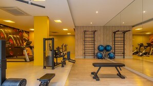 Un gimnasio con equipo de ejercicio, una banca y un espejo grande.