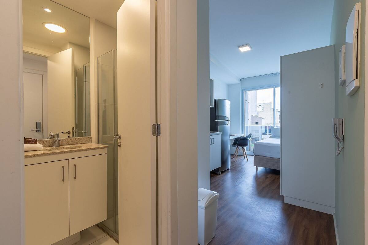 Un appartement moderne comprenant une salle de bain, un coin cuisine et un espace de vie avec un canapé et une table à manger.
