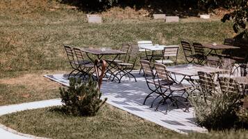Un espacio de patio al aire libre con mesas y sillas dispuestas sobre una terraza de madera.