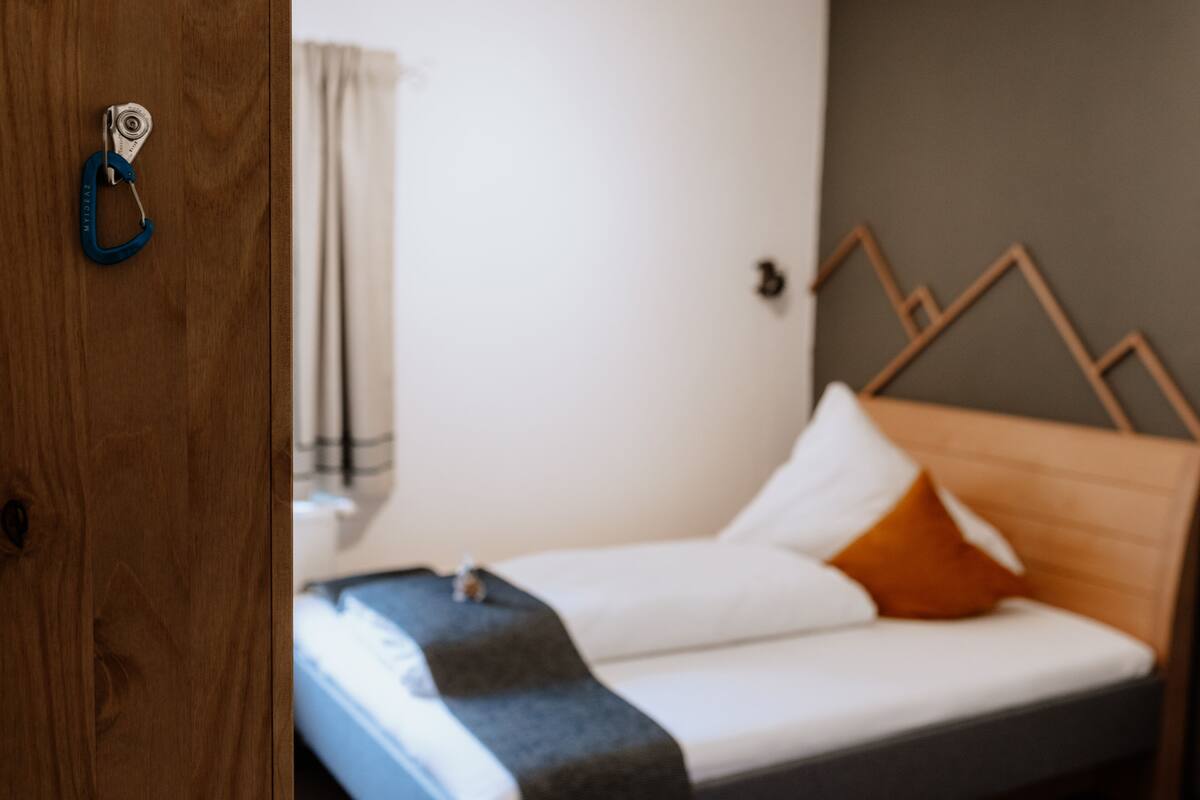 Une chambre à coucher avec une tête de lit en bois, un lit avec des oreillers blancs et orange, et une couverture bleue.