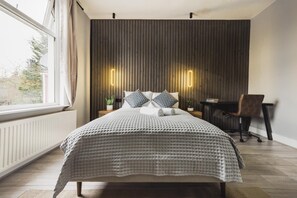 A modern bedroom with a large bed, a desk, and a chair.