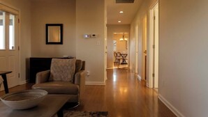 A spacious living room with a sofa, a dining table, and a hallway leading to a dining area. - NEW!  Charming Vineyard Cottage in the heart of the Russian river wine country! (Santa Rosa)