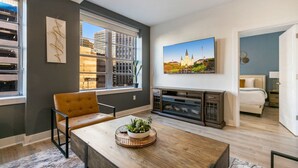 Un salon moderne avec un canapé, une table basse et un tableau représentant un paysage urbain.