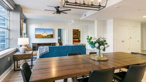 Un espace repas moderne avec une table en bois, des chaises noires, un canapé bleu et un lustre.