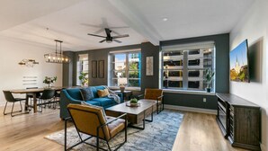Un salon moderne avec un canapé bleu, une table basse en bois et un coin repas comprenant une table et des chaises en bois.