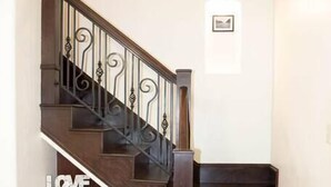 Un escalier en bois, doté d’une finition foncée et de balustres décoratives.