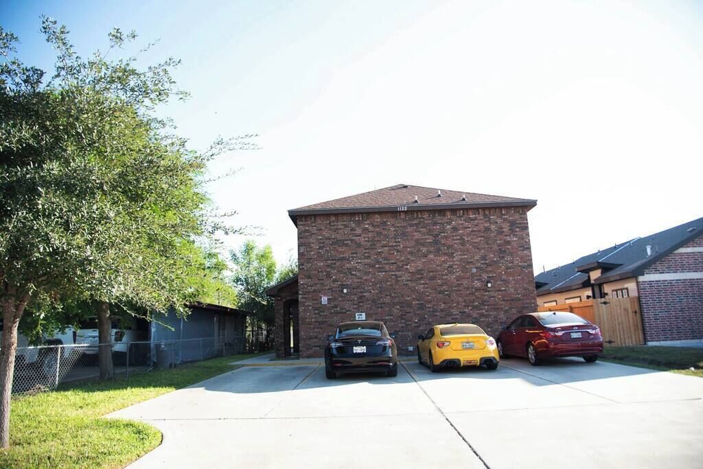A parking area with three cars parked in front of a brick building.