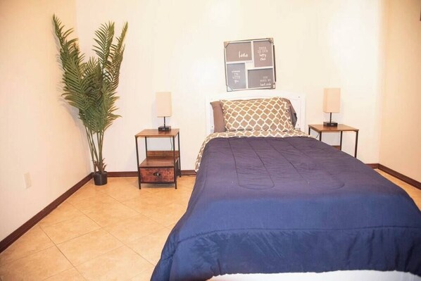 A bedroom with a large bed, two bedside tables, a wall-mounted light, a potted plant, and a motivational quote board. - 3BD 2BT town suite minutes away Medical Center (Edinburg)
