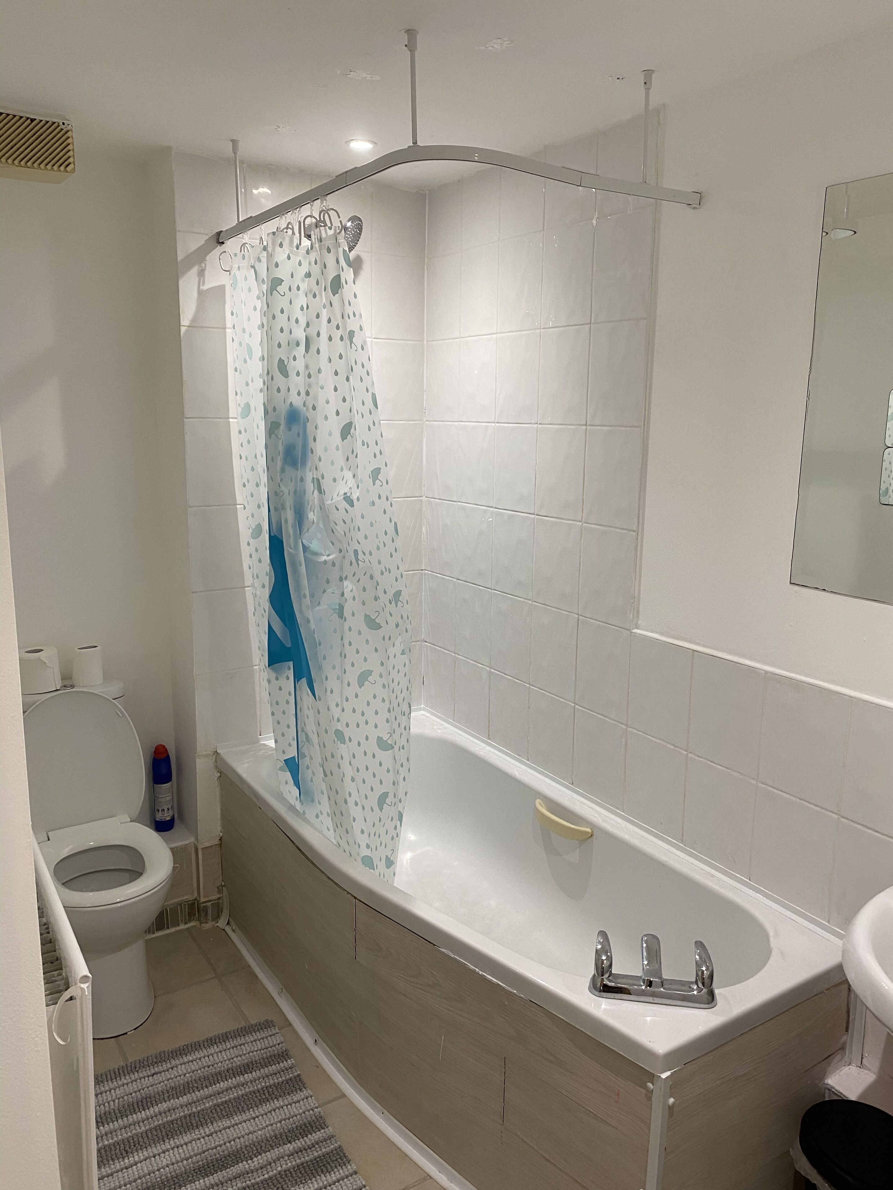 A bathroom with a bathtub, toilet, and a shower curtain.