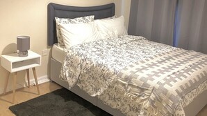 A neatly arranged bedroom with a bed, bedside table, lamp, and a dark rug. - Impeccable 2-bed Apartment in London (London)