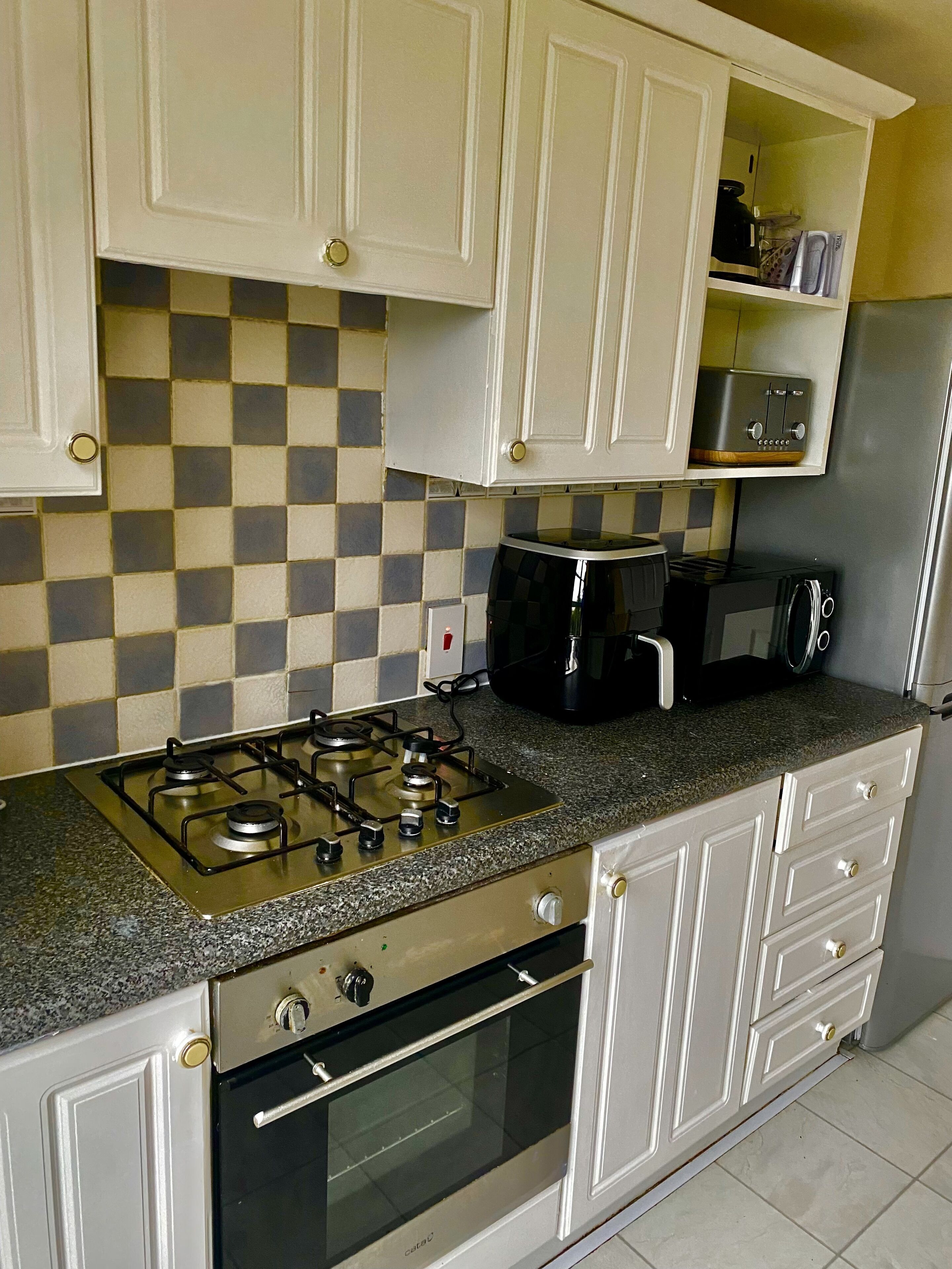 A kitchen with white cabinets, a gas stove, a microwave, and a toaster.