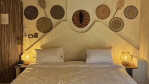 A bed with white linens, a woven ceiling light fixture, and decorative woven wall art. - IL CAMPO Ecolodge & Boutique Hotel (Giza)