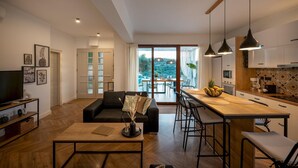 Een moderne woonkamer met een bank, salontafel en een televisie. Er is een balkon met uitzicht op het landschap.