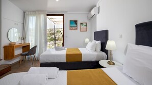 Een hotelkamer met twee bedden, een bureau, een stoel en uitzicht op de omgeving.