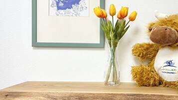 A framed map on a wall, a vase with yellow tulips, and a plush toy on a shelf.