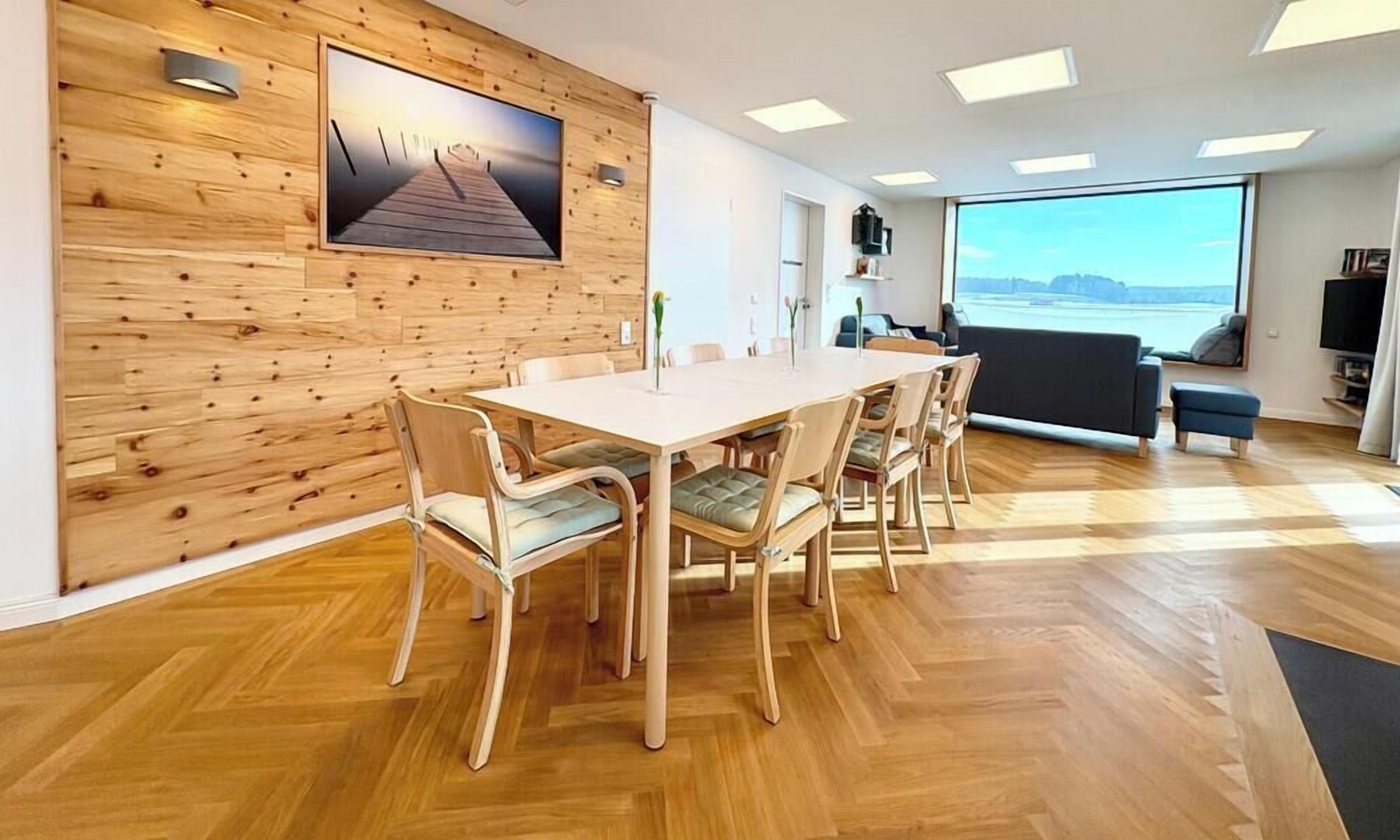 Un'area pranzo moderna con una parete in legno, un'ampia finestra con vista e un televisore a schermo piatto.