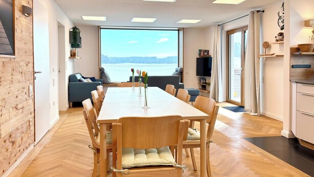 Un espace de repas moderne, doté d’une grande table et de chaises, d’un canapé et offrant une vue sur l’extérieur.