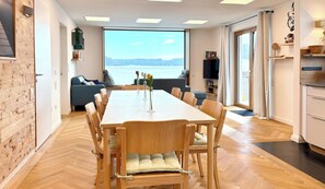 Un espace de repas moderne, doté d’une grande table et de chaises, d’un canapé et offrant une vue sur l’extérieur.