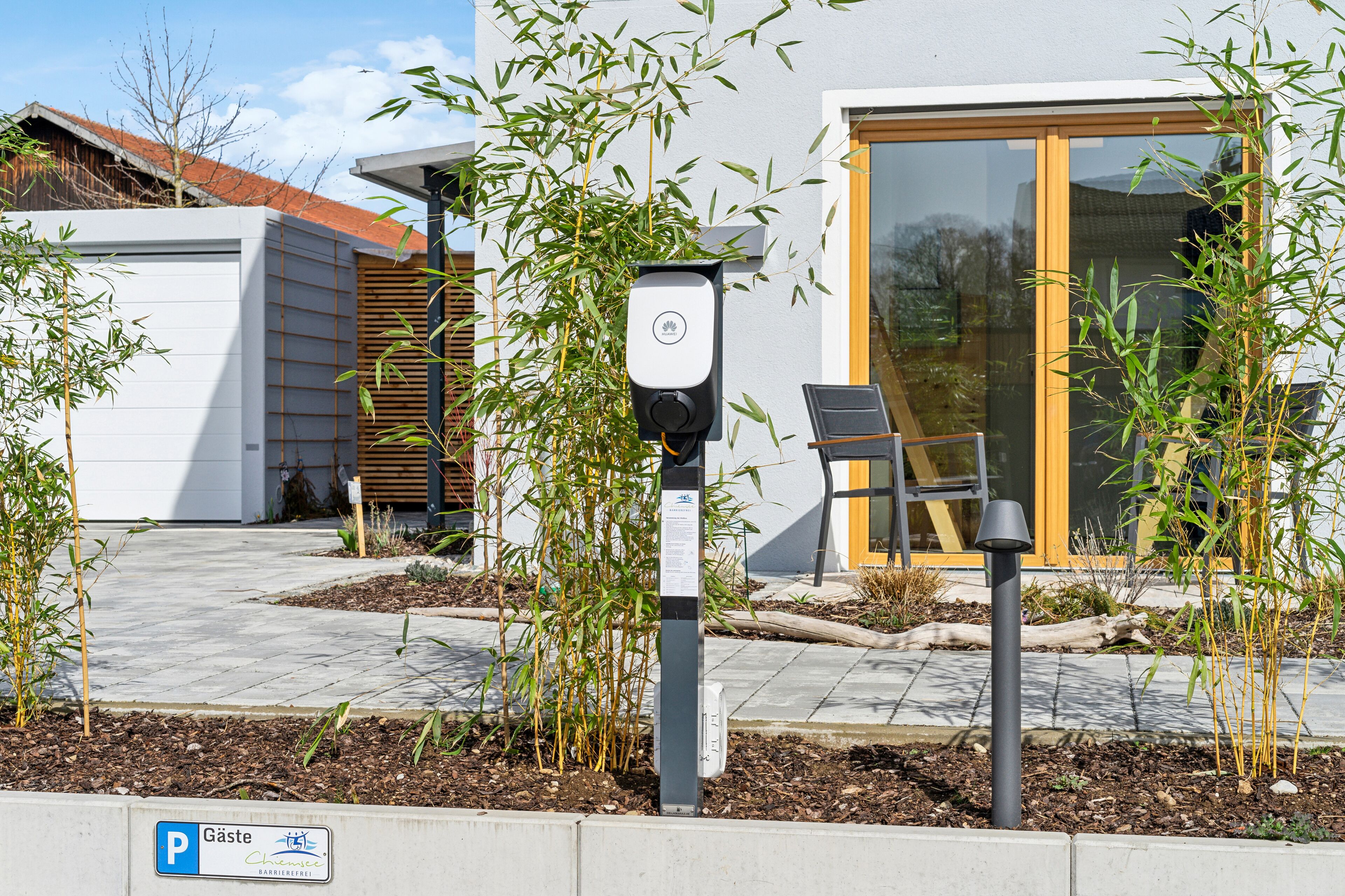 A modern building with a glass door entrance, a parking meter, and a small garden area with bamboo plants.