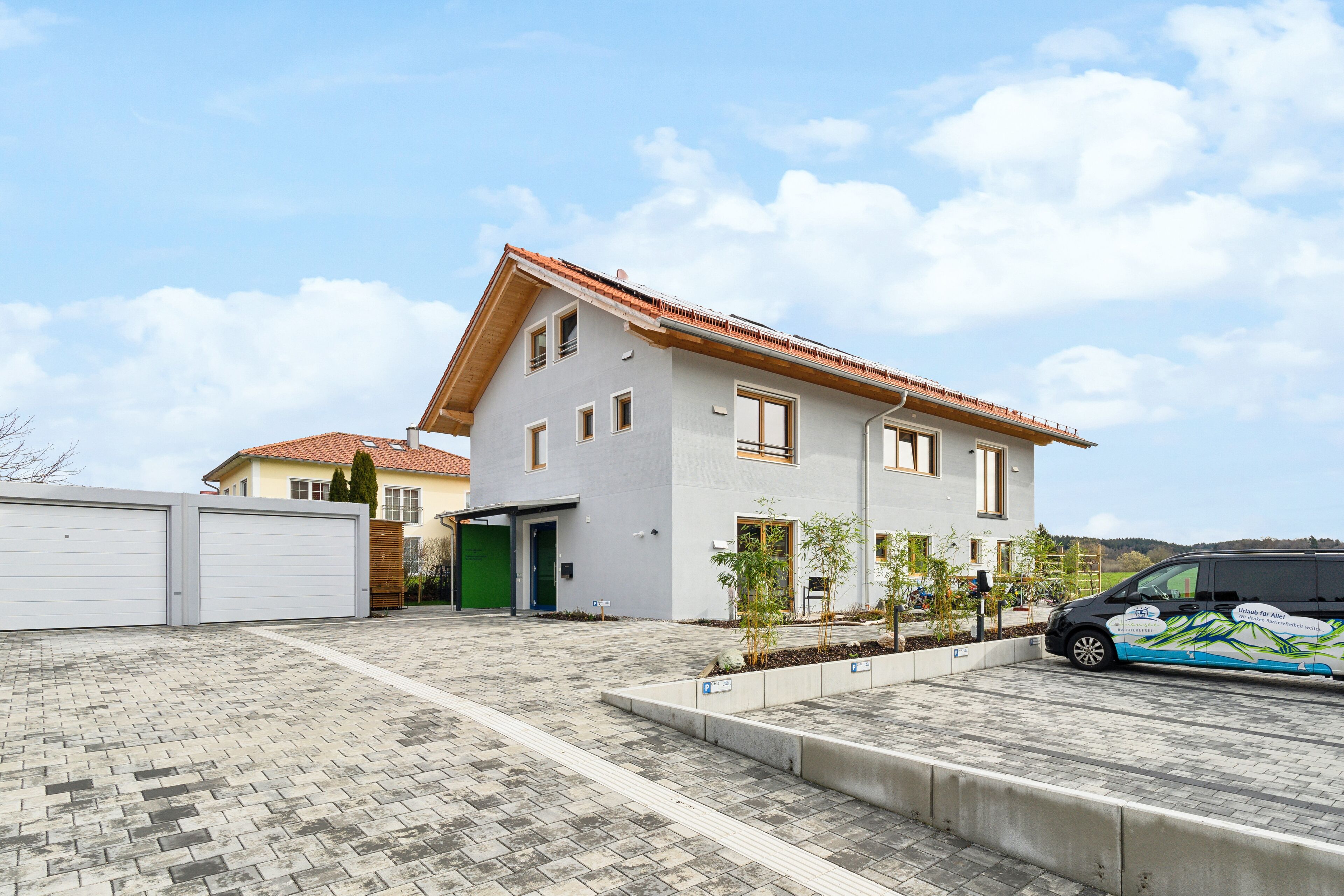 A modern two-story house with a tiled roof, a garage, and a paved driveway.