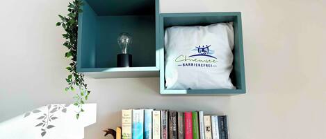 A shelf with books and a pillow with a logo.