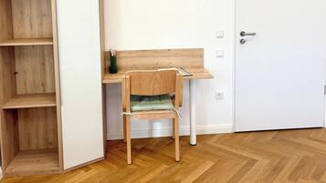 A room with a wooden desk, a chair, and a white door.