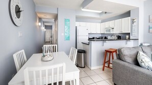 Une cuisine moderne avec des meubles blancs, un réfrigérateur en acier inoxydable et un plan de travail sur lequel se trouve une machine à café.