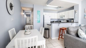 Una cocina moderna con armarios blancos, un refrigerador de acero inoxidable y una encimera con una cafetera.