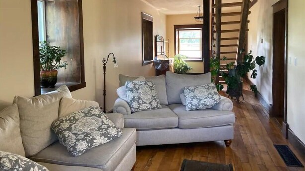 A cozy living room with a grey sofa, patterned cushions, and a wooden floor. - Williamsford Blacksmith Shop (Williamsford)