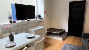 A modern, well-lit room with a desk, chair, and a large window. - Charming Studio in Bond Street (London)